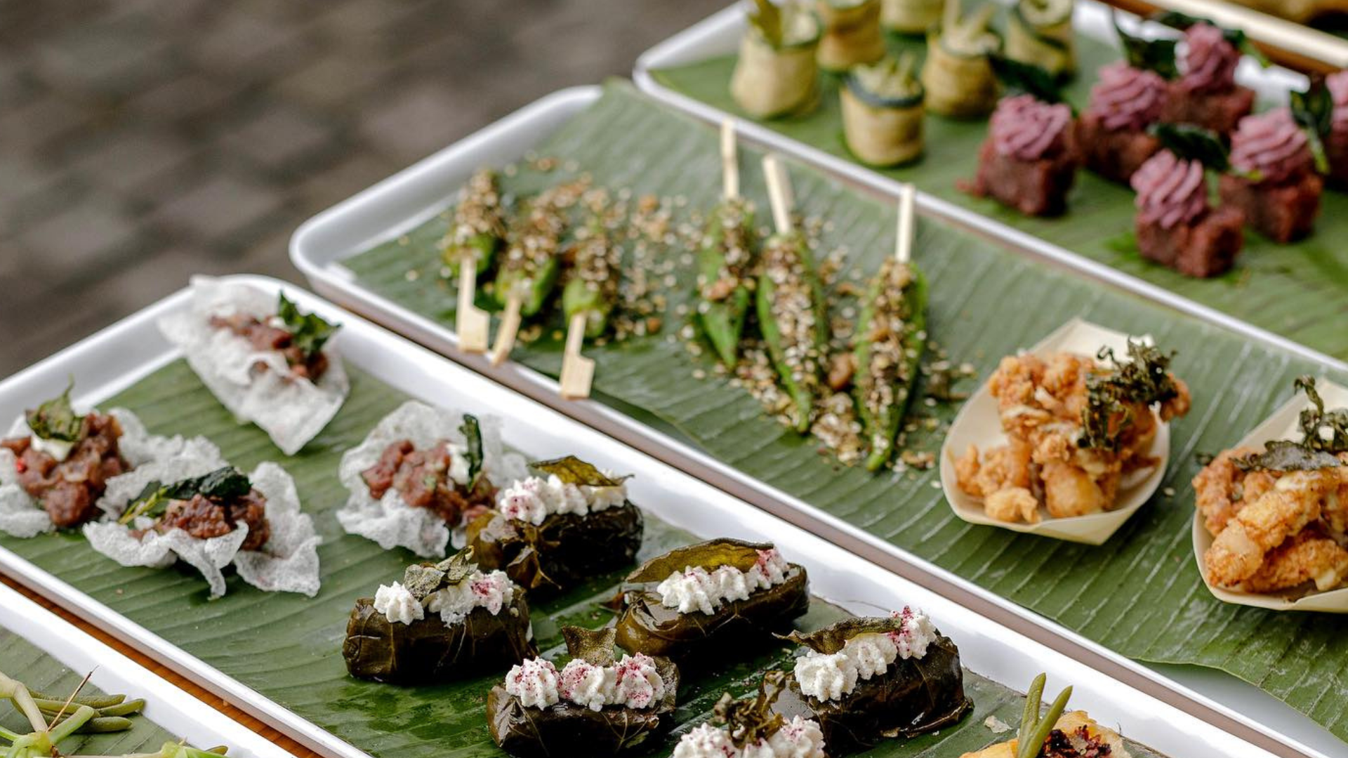 Close up of canapes on plates with banana leaves.